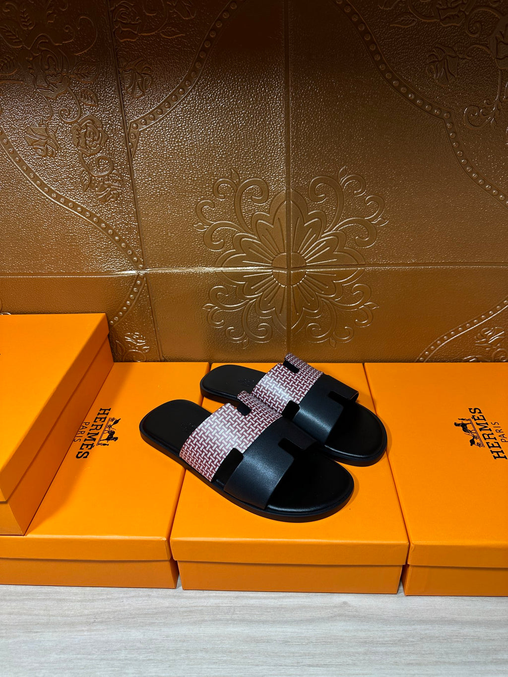 Hermes sandals with black slide sole and light patterned strap across the foot, pair