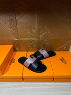 Hermes sandals with black slide sole and light patterned strap, open toe, angled view