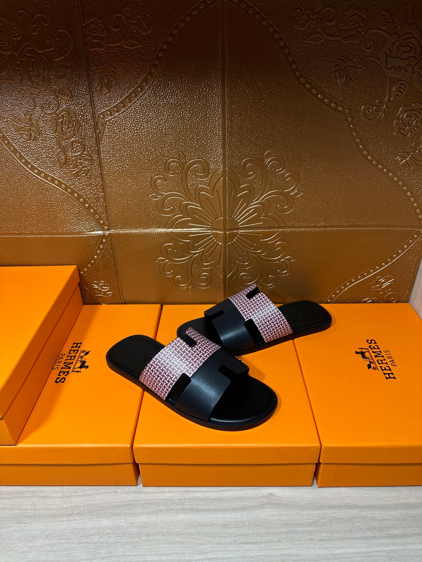 Hermes sandals with black slide sole and light patterned strap, open toe, angled view