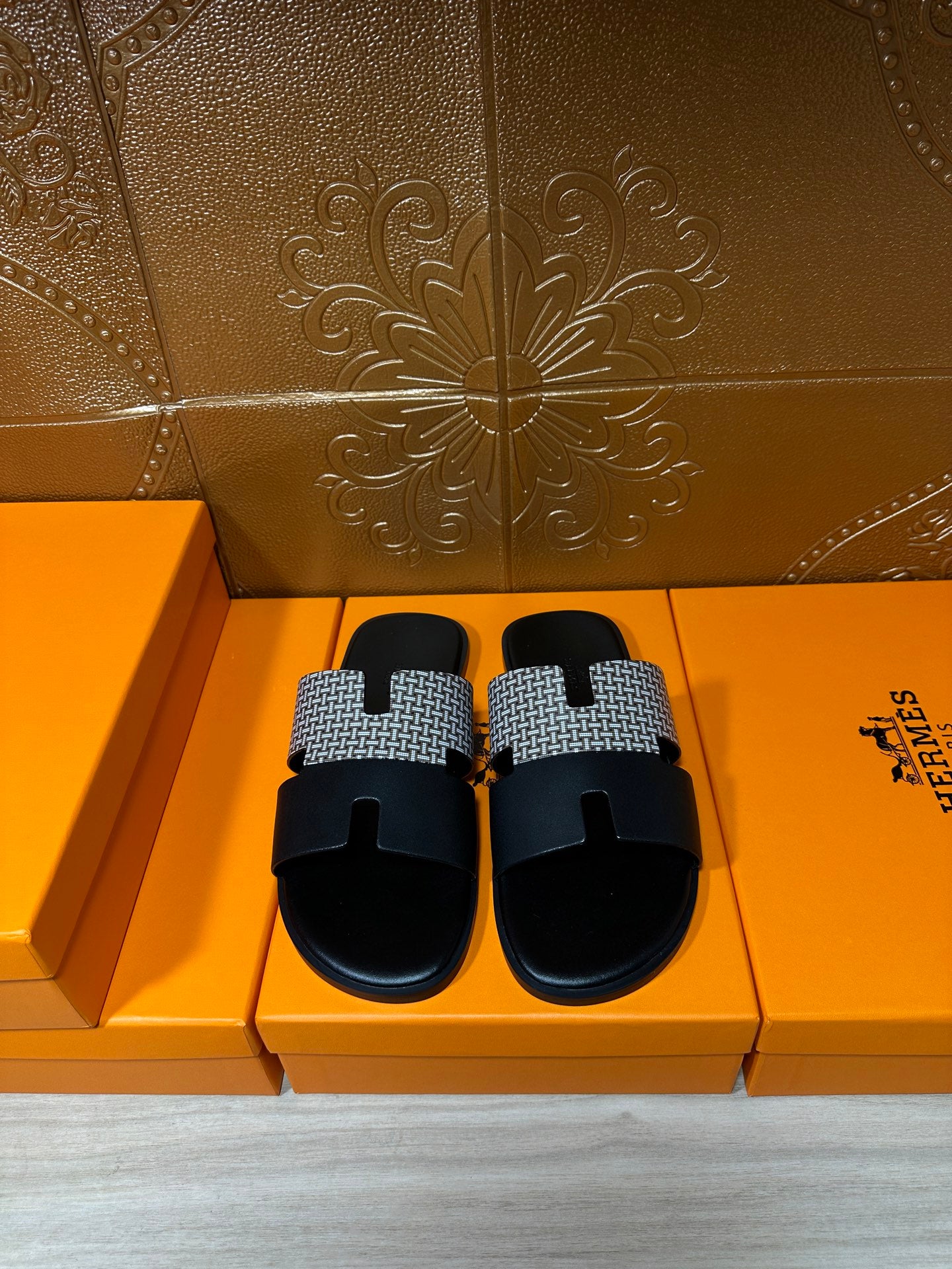 Hermes slide sandals with black footbed and textured gray woven strap, shown as a pair