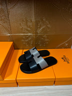 Hermes slide sandals, black leather-look slide with patterned gray strap and square buckle tab