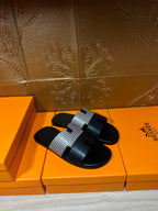 Hermes slide sandals with black sole and wide woven gray strap with black buckle detail