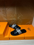 Hermes slide sandals with black slide base and woven gray strap across the foot