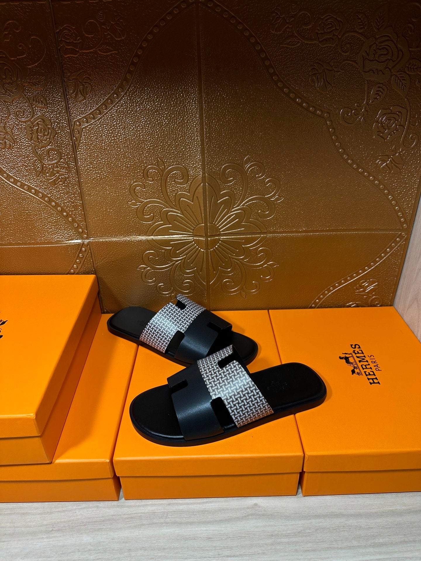 Hermes slide sandals with black slide base and woven gray strap across the foot