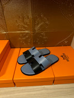 Blue woven slide sandals with black strap bands and black buckle, single sandal view