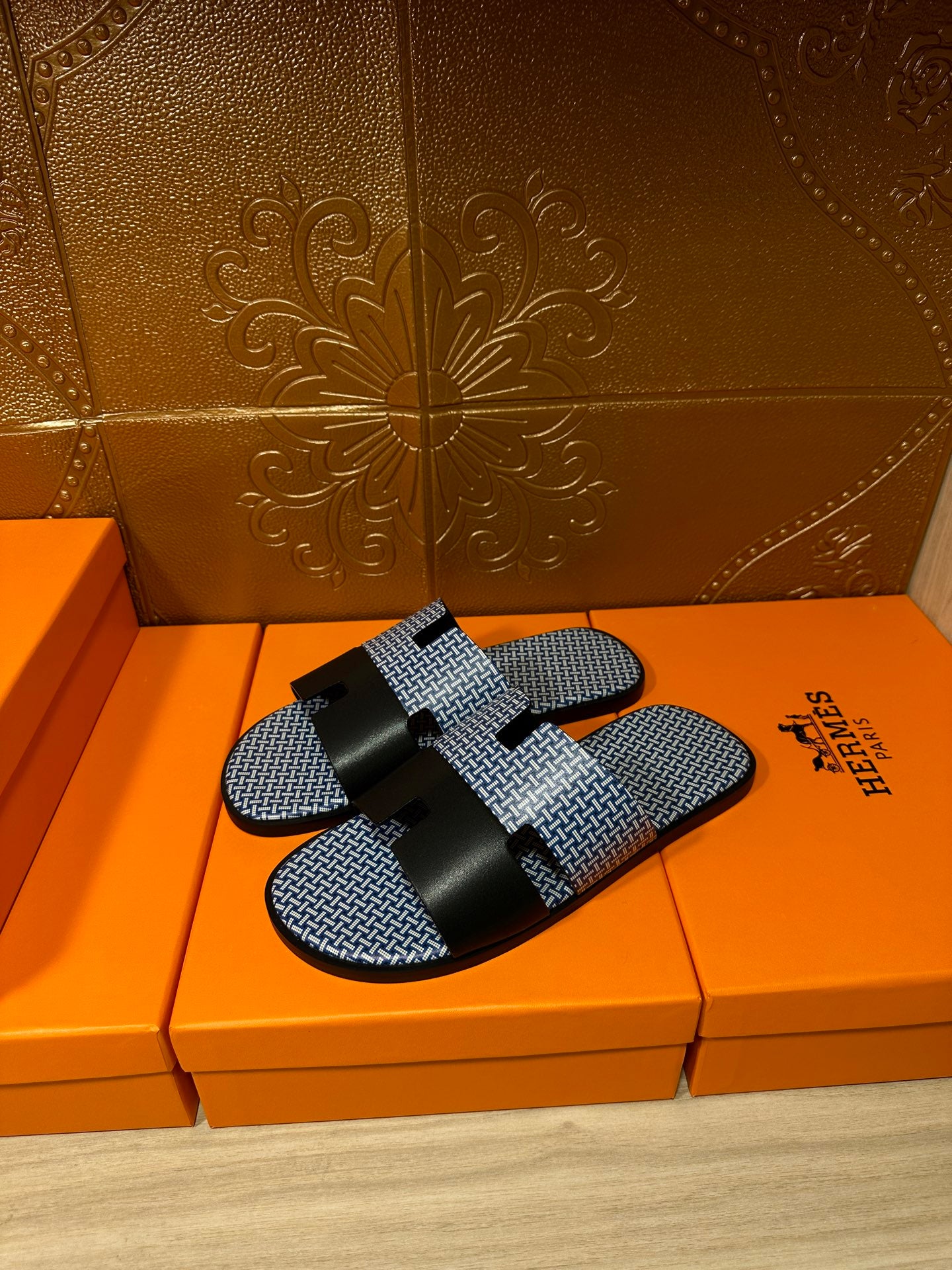 Blue woven slide sandals with black strap bands and black buckle, single sandal view