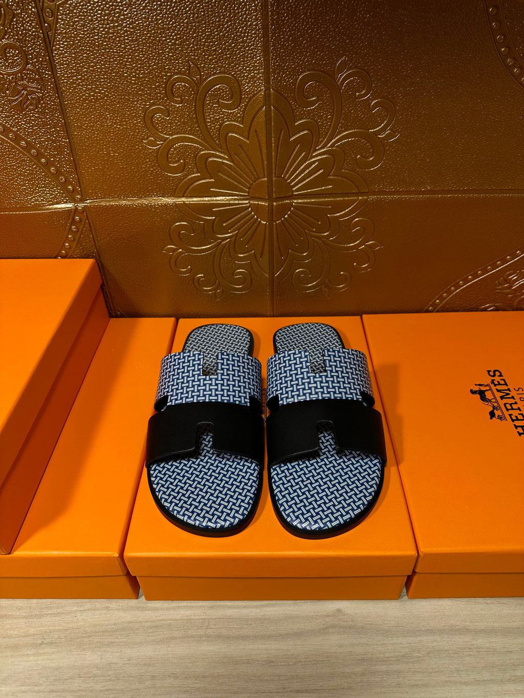 Blue woven slide sandals with two black strap bands and black buckle, pair