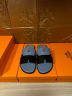 Blue woven slide sandals with two black strap bands and black buckle, pair