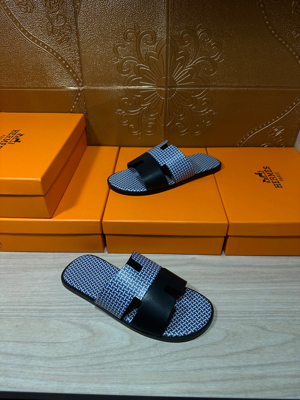 Blue woven slide sandals with black strap bands and buckle, pair resting