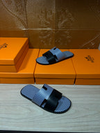 Blue woven slide sandals with black strap bands and buckle, pair resting