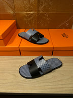 Blue woven slide sandals with black strap bands and buckle, pair on display