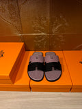 Slide sandals with pink textured upper and black wide buckle strap; pair of shoes