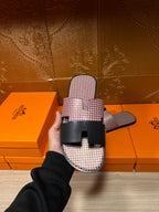 Pink textured slide sandals with black buckle strap; top view held in hand