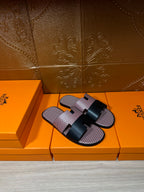 Slide sandals featuring pink textured footbed and black center buckle strap; side view