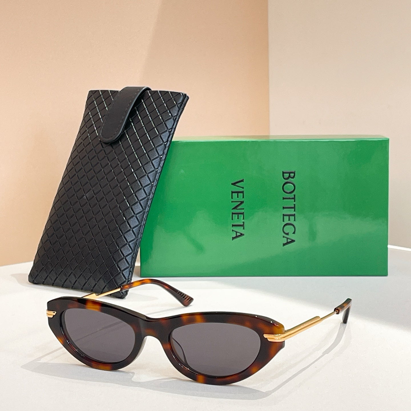 Tortoise cat-eye sunglasses with gold-tone temples and dark lenses, with black textured case