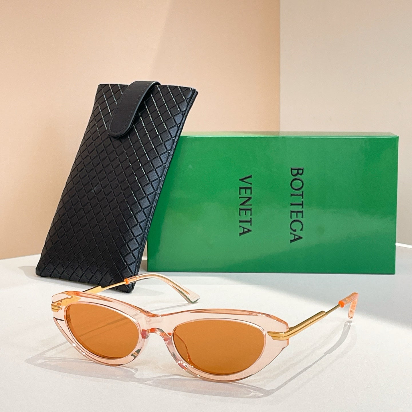 Orange-tinted cat-eye sunglasses with gold-tone temples and amber lenses, with black case