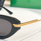 Close-up of black cat-eye sunglasses with gold-tone temple arms and dark lenses