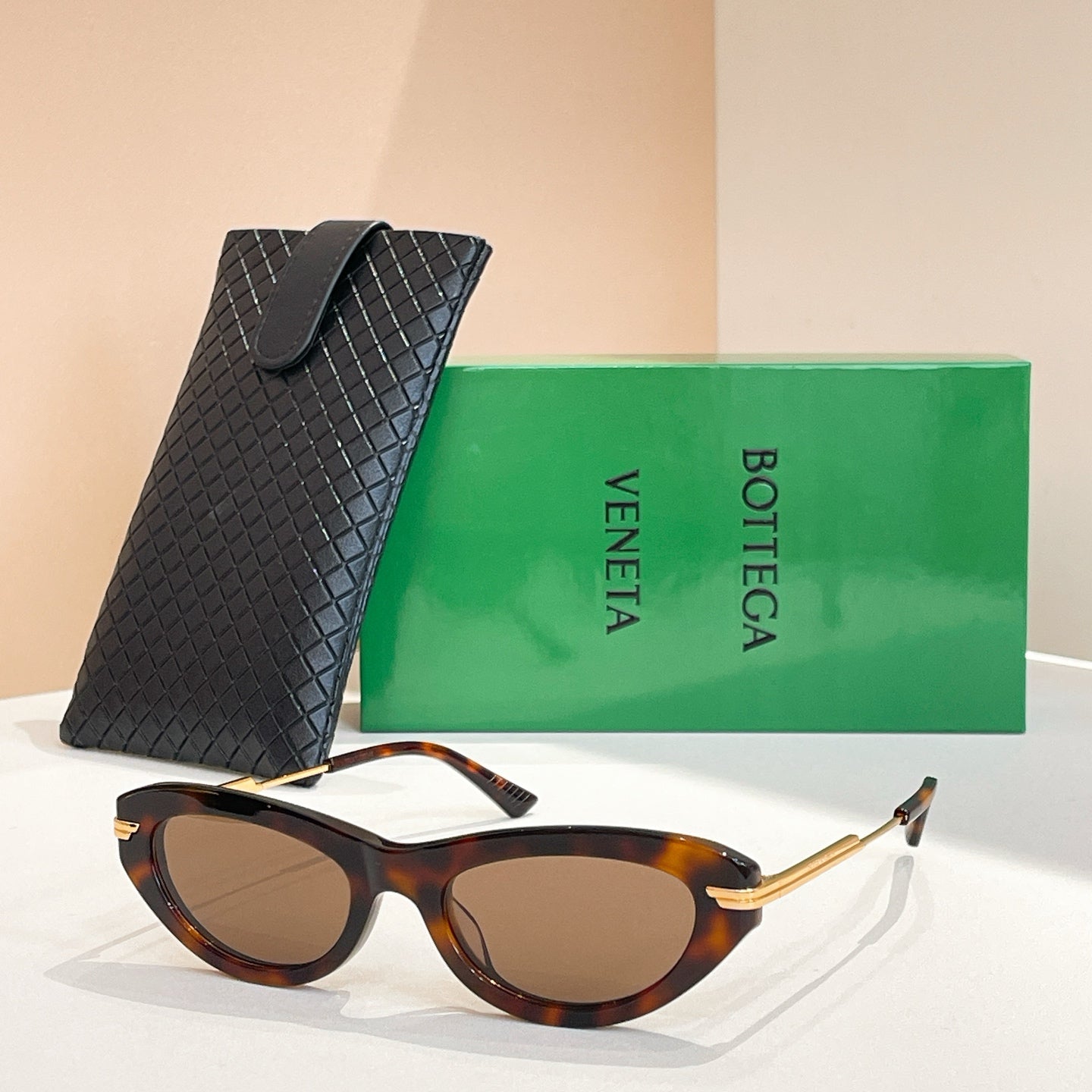 Tortoise cat-eye sunglasses with gold-tone temples and dark lenses, with black textured case
