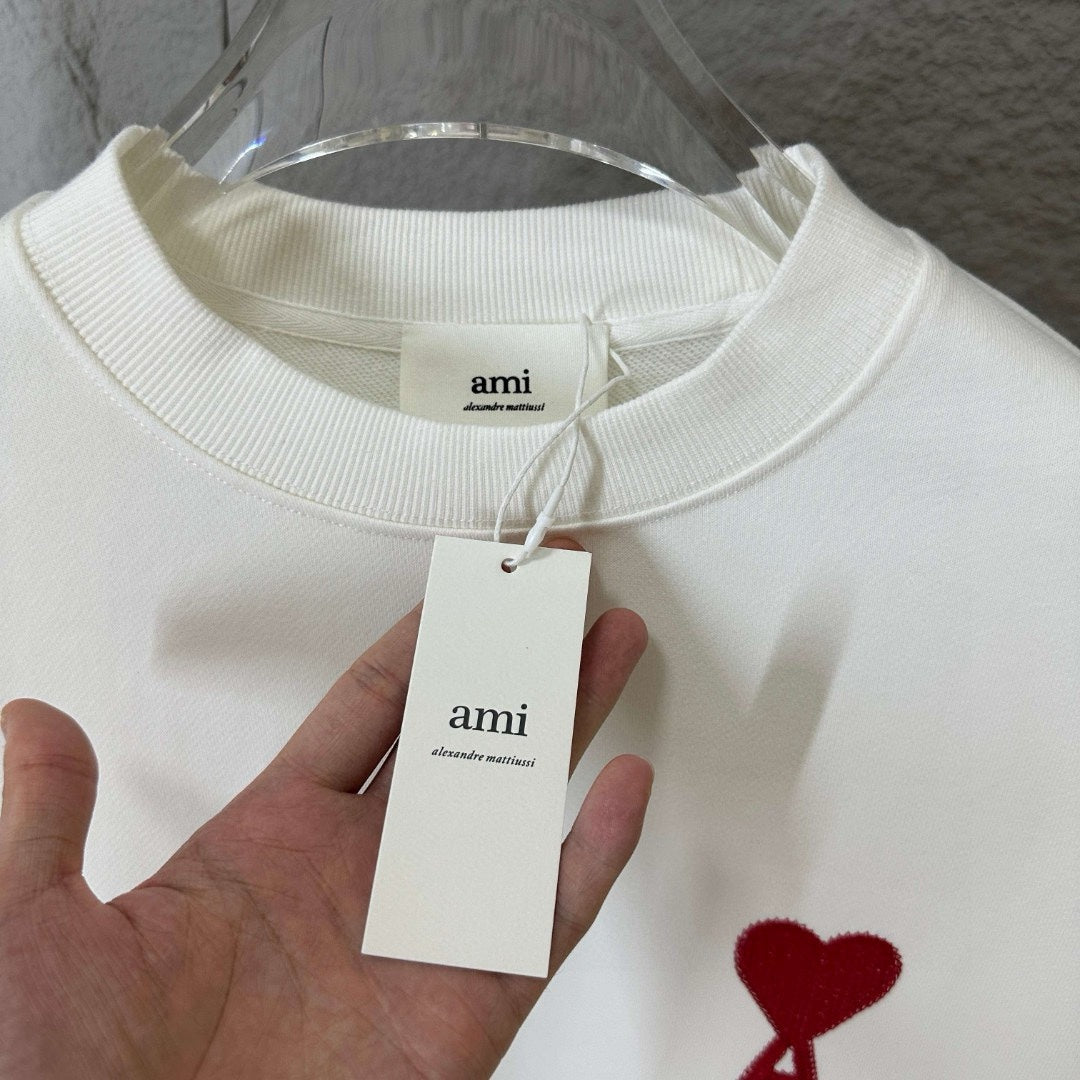 White crewneck sweatshirt with fabric tag at collar and red heart A logo