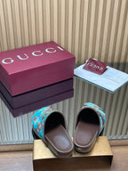 Gucci slide sandals showing open toe, teal GG-pattern upper with gold buckle on brown base.