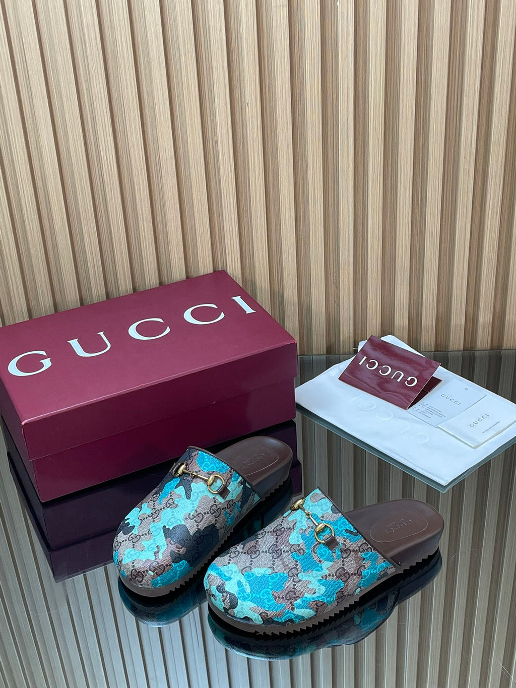 Gucci mule-style sandals with teal GG-pattern straps and gold buckle, brown footbeds.