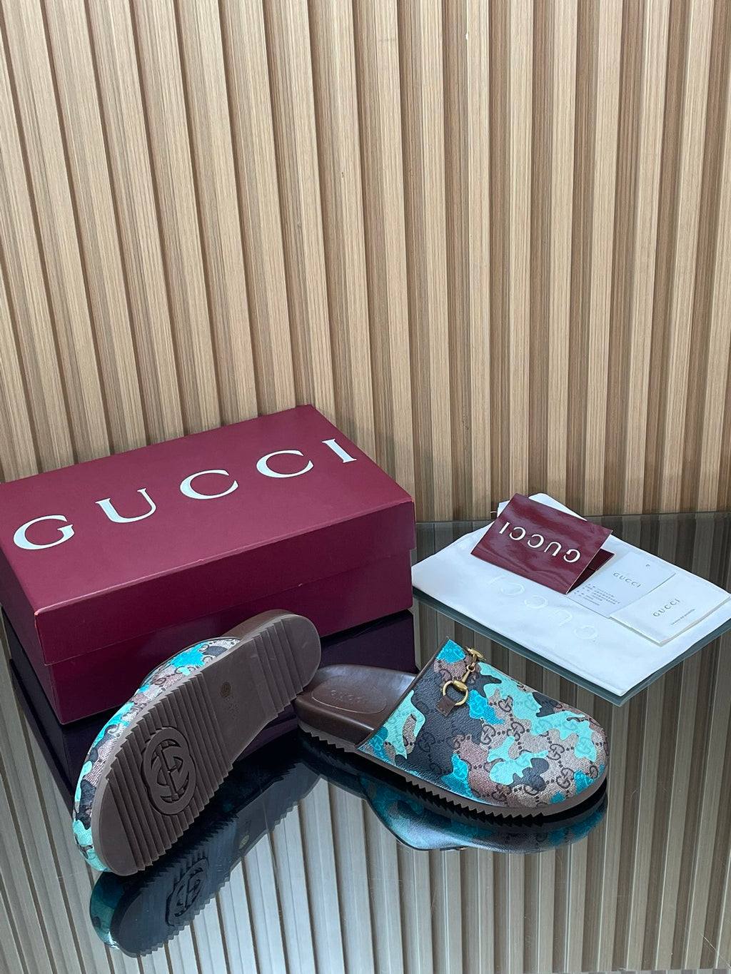 Gucci sandals from the side with textured outsole, teal GG-pattern upper and gold buckle.
