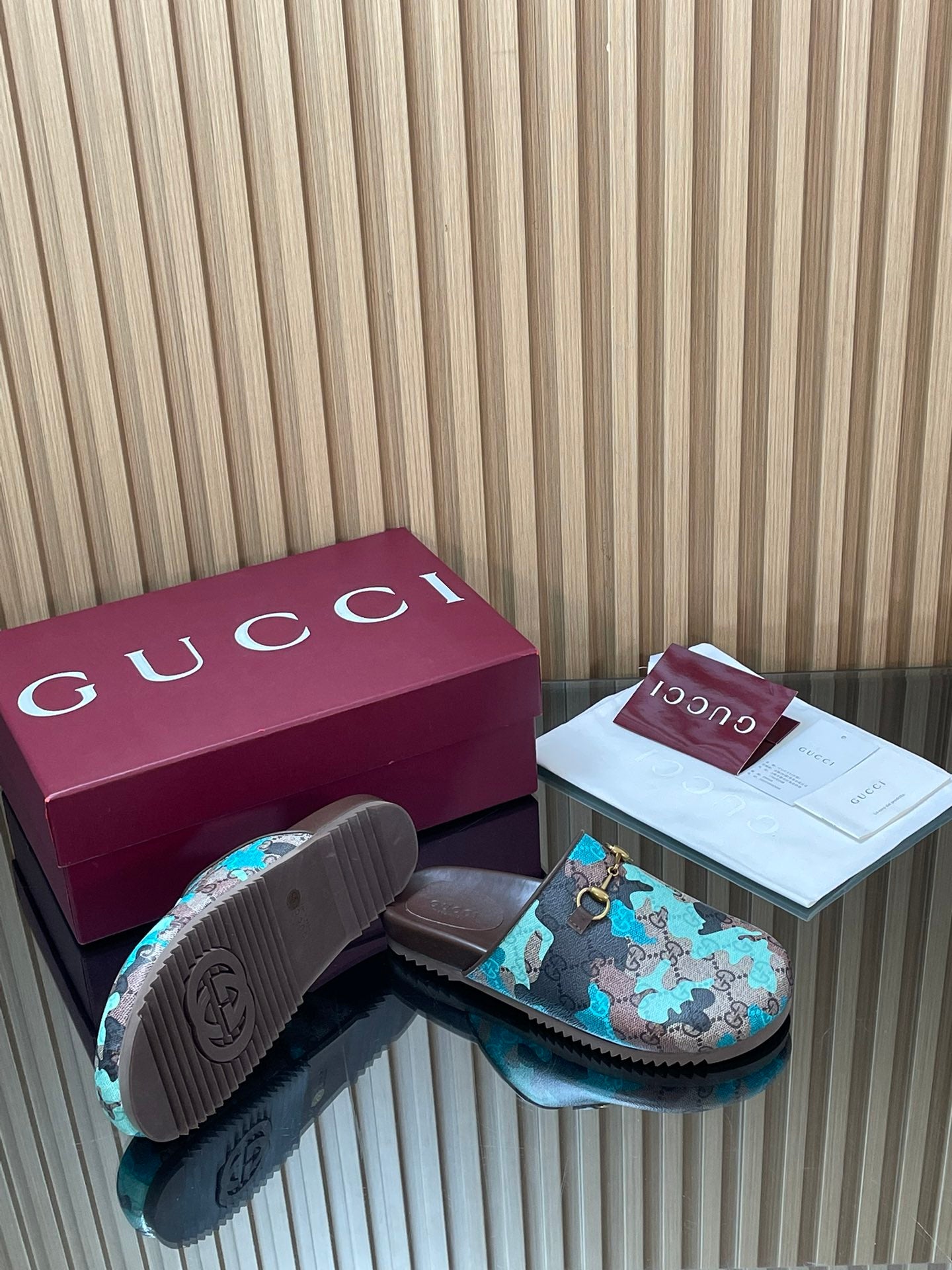 Gucci sandals from the side with textured outsole, teal GG-pattern upper and gold buckle.