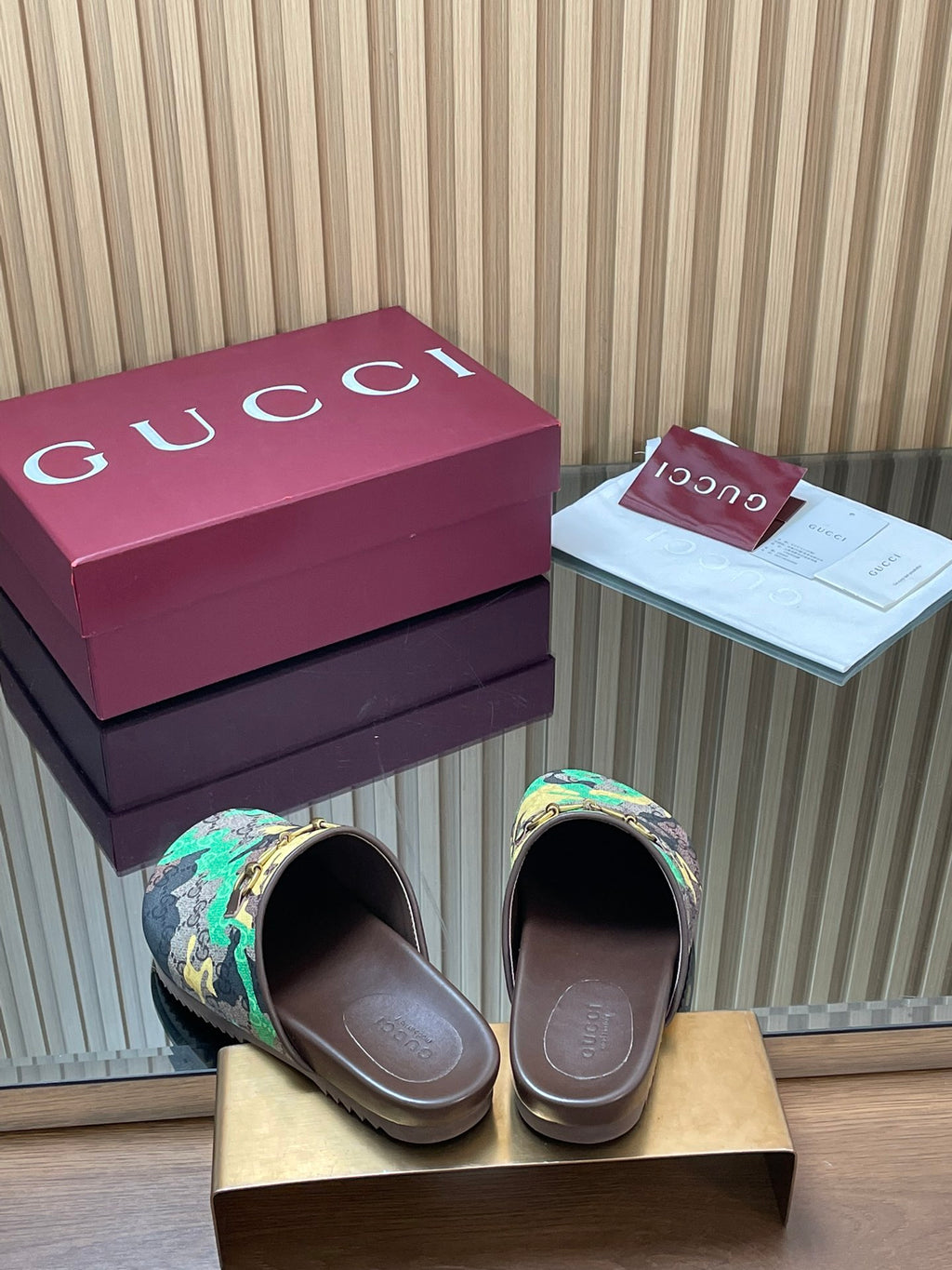 Gucci slide sandals shown from front, multicolor logo print and brown footbed