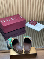 Gucci slide sandals shown from front, multicolor logo print and brown footbed