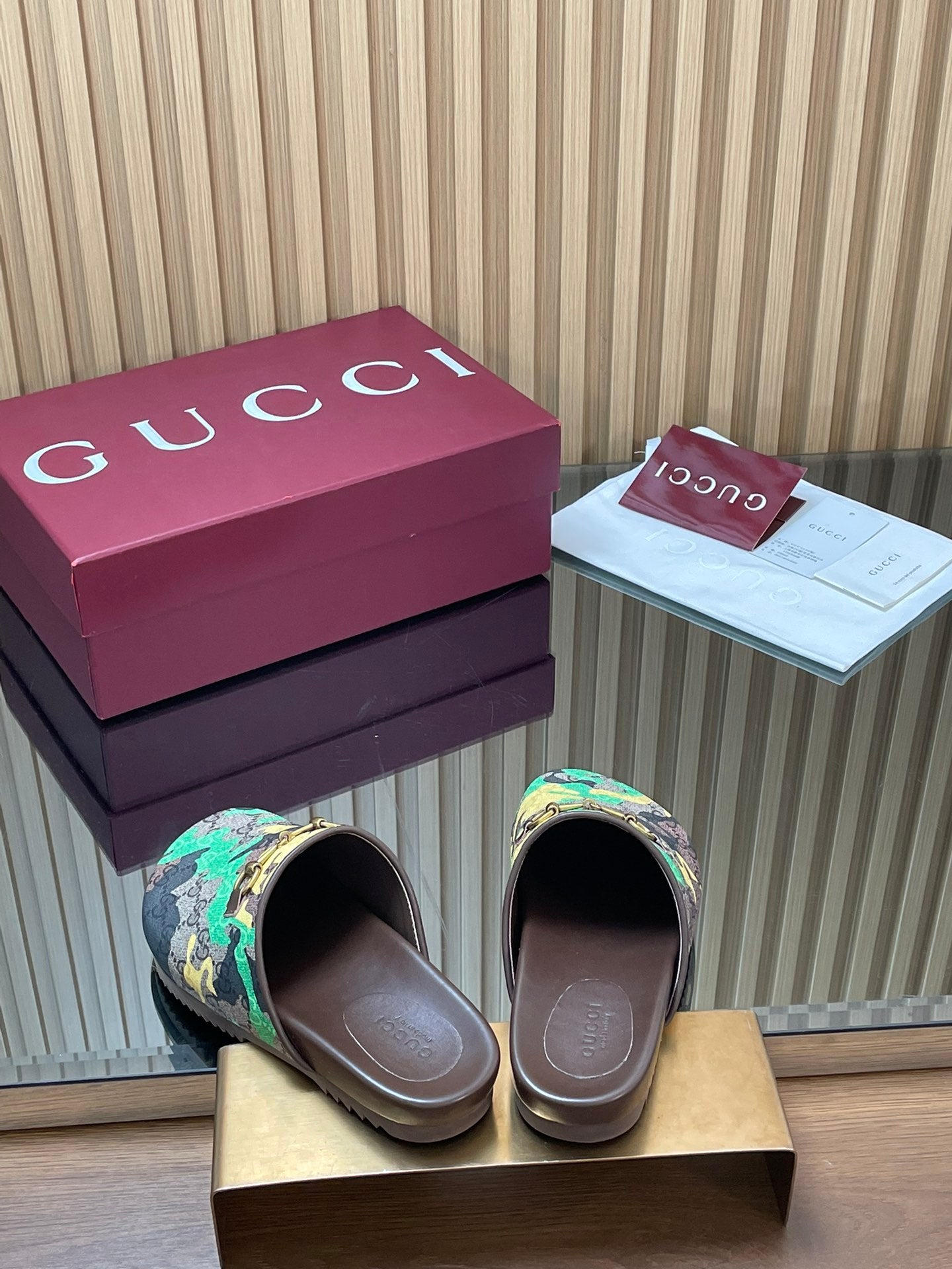 Gucci slide sandals shown from front, multicolor logo print and brown footbed