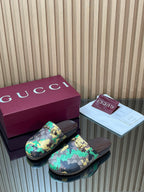 Gucci logo-pattern slide sandals with green-blue tones and gold buckle on dark sole