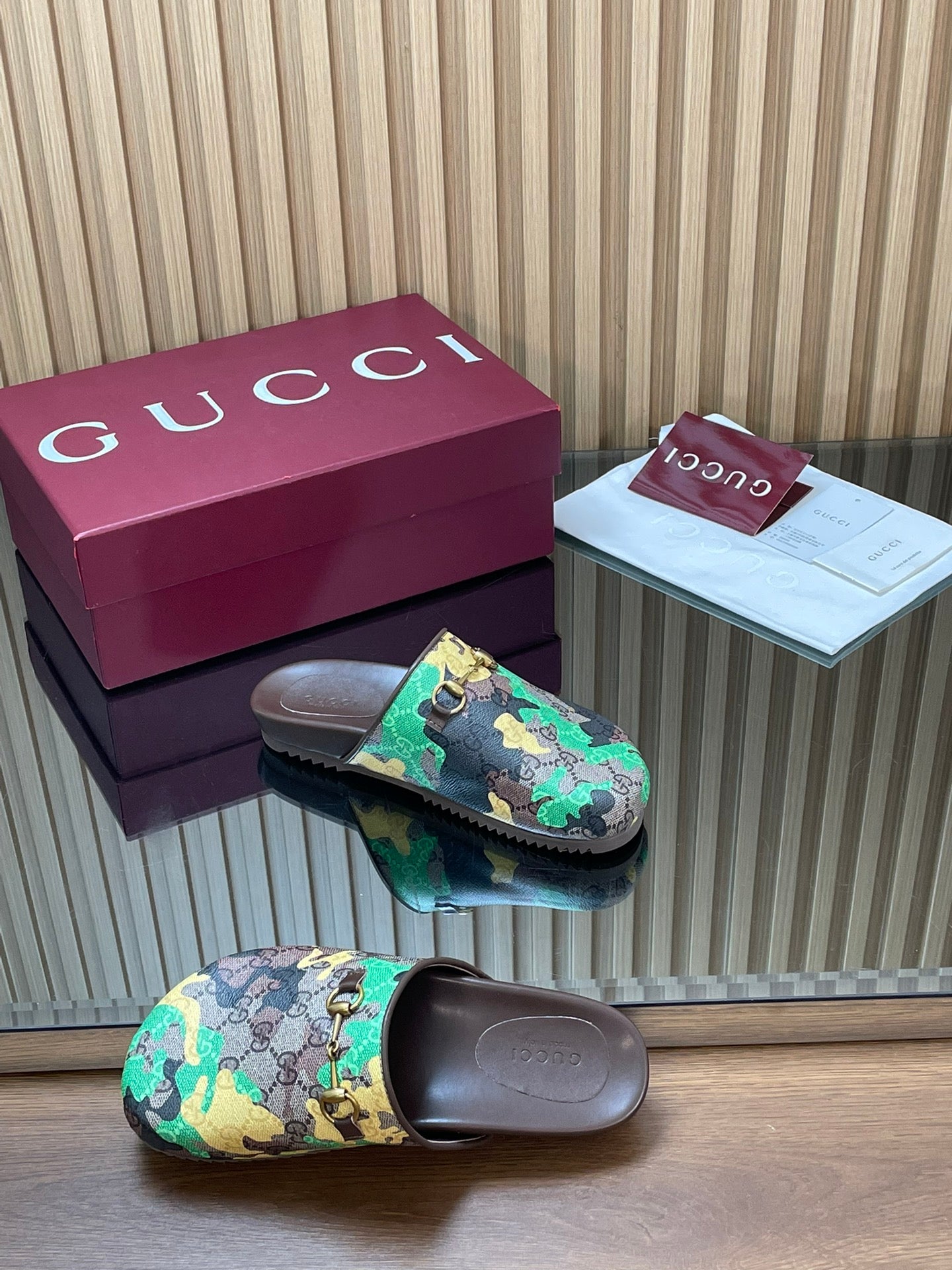 Gucci slide sandals pair on side view, multicolor upper with gold hardware