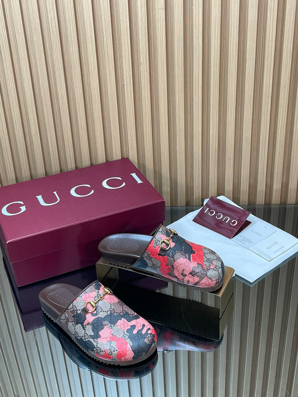 Gucci slide sandals, pink-and-black patterned upper with gold-tone buckle and dark sole