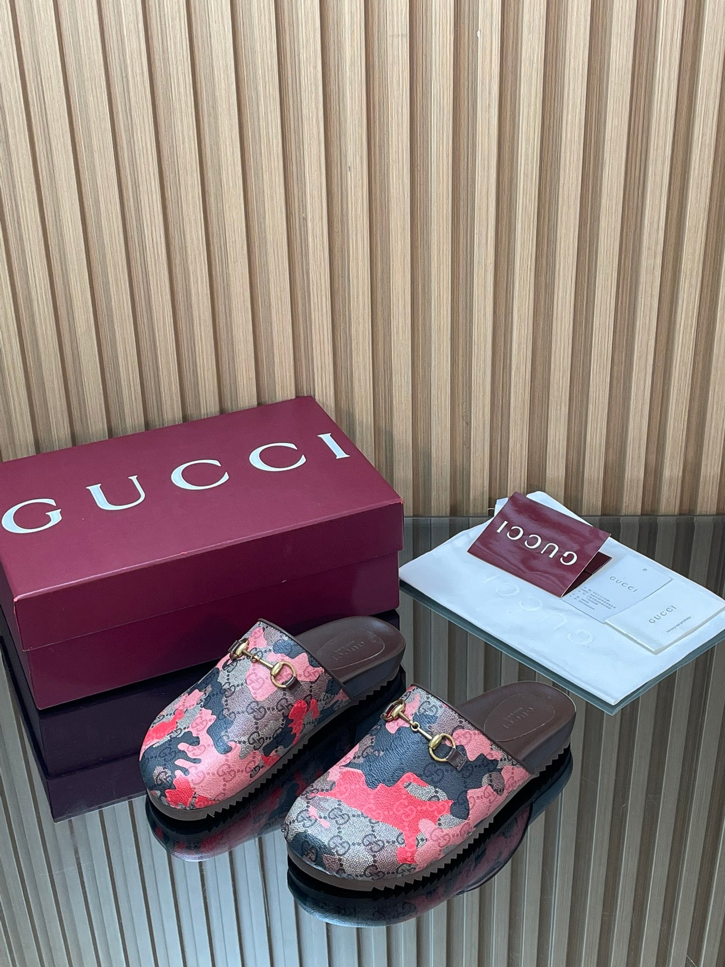 Gucci slide sandals pair, pink-and-black patterned fabric with gold-tone buckle detail