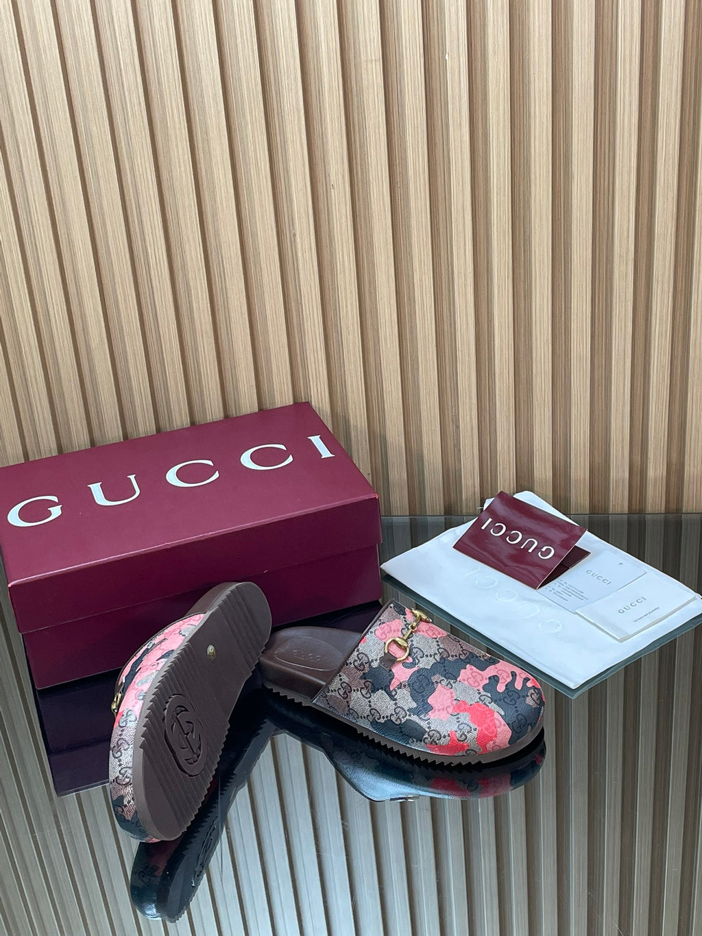 Gucci slide sandals with pink-and-gray patterned upper and metal logo buckle, side profile