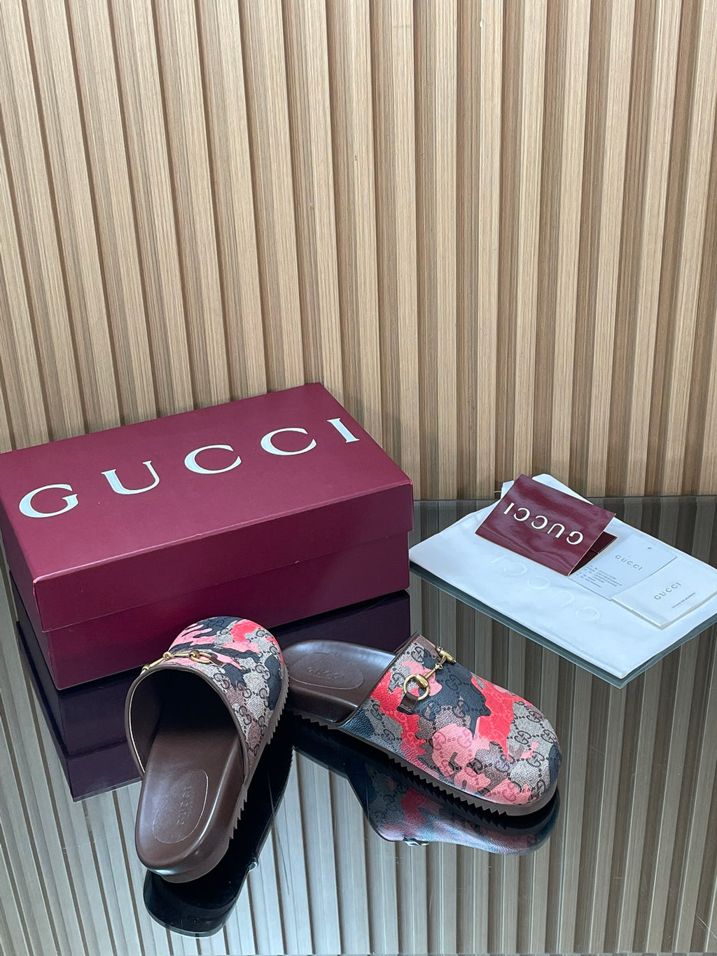 Gucci slide sandals, side view of pink-and-black patterned straps with gold-tone buckle