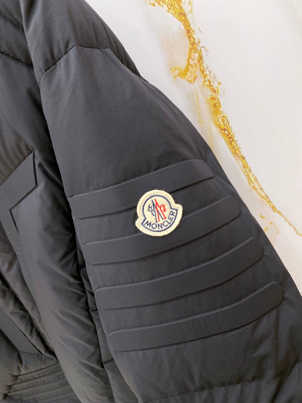 Moncler long puffer jacket sleeve with logo patch on dark quilted shoulder