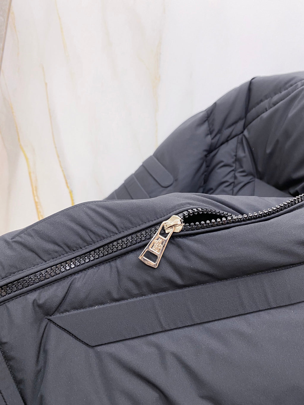 Moncler long puffer jacket zipper close-up on dark quilted fabric