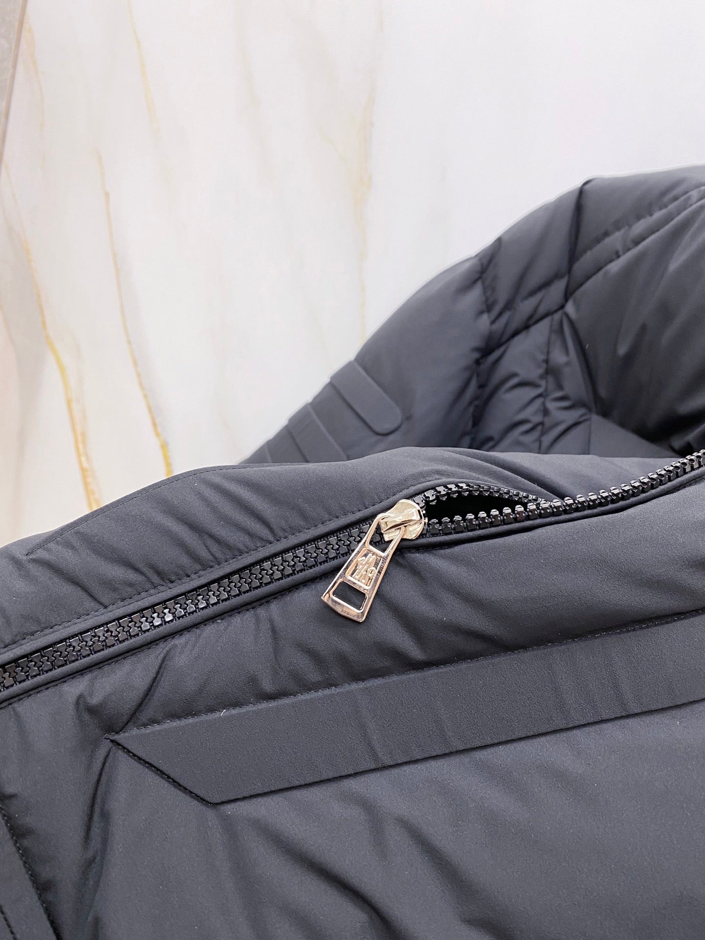 Moncler long puffer jacket zipper close-up on dark quilted fabric