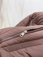 Moncler puffer jacket zipper close-up, dark brown with metal pull tab.