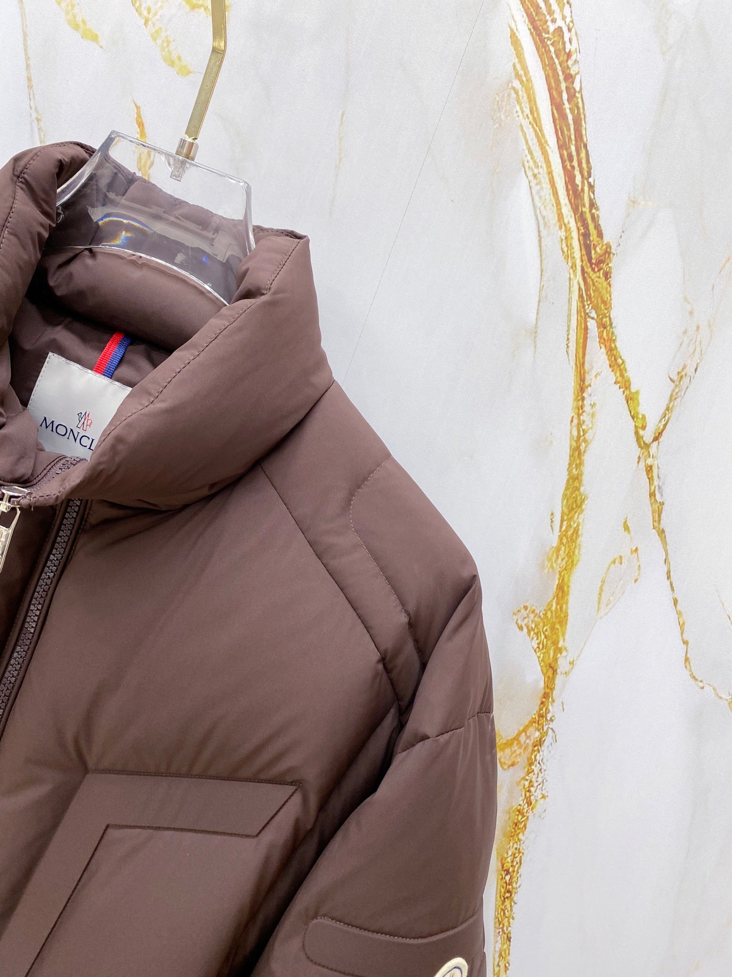 Moncler puffer jacket side panel and pocket, dark brown quilted padding.
