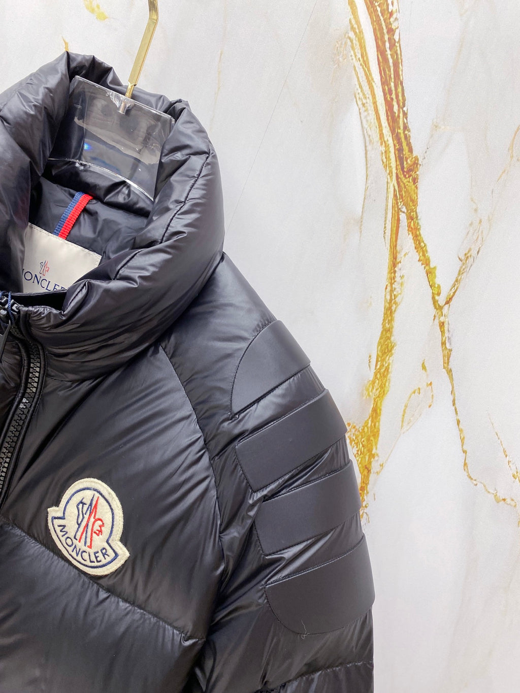 Moncler long puffer jacket sleeve close-up, dark navy quilted panels and logo
