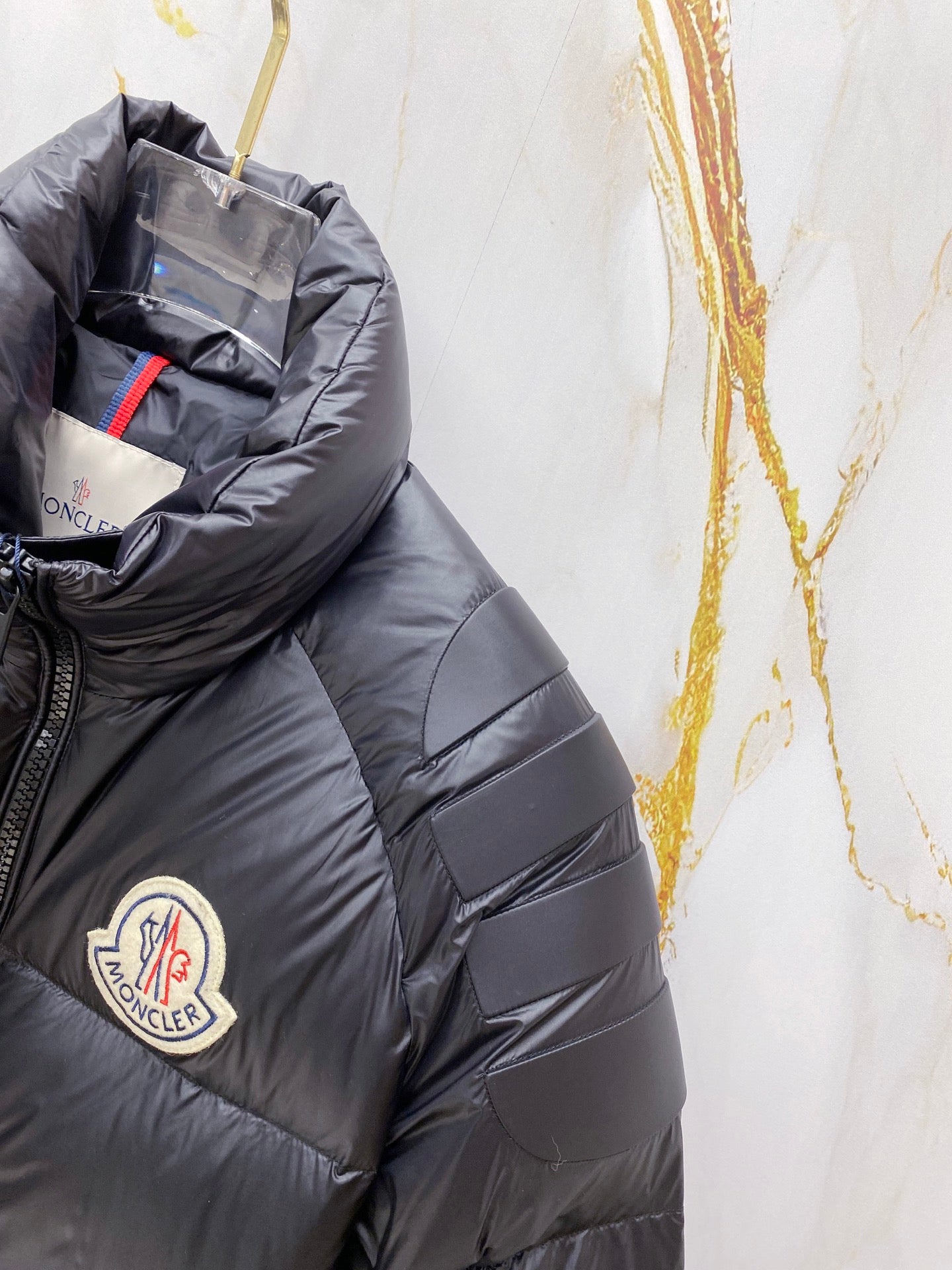 Moncler long puffer jacket sleeve close-up, dark navy quilted panels and logo