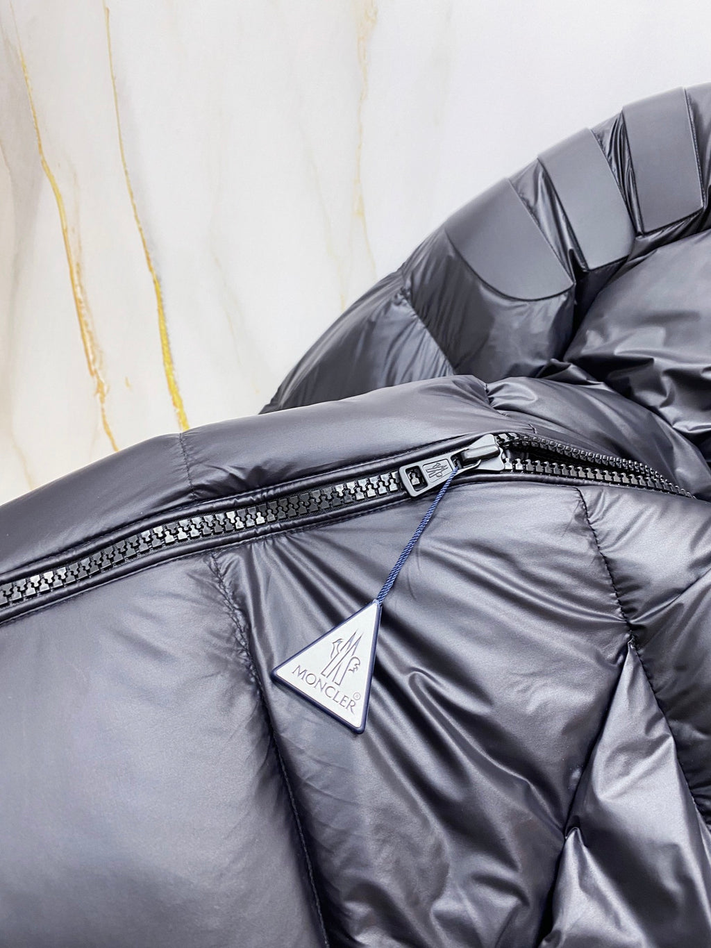 Moncler long puffer jacket chest close-up, dark navy with zip and logo patch