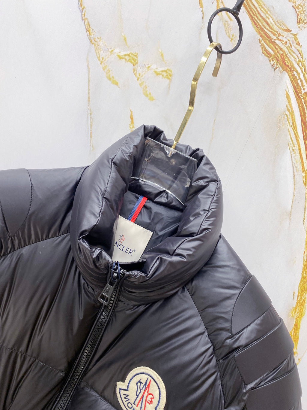 Moncler long puffer jacket close-up, dark navy hooded collar and logo badge