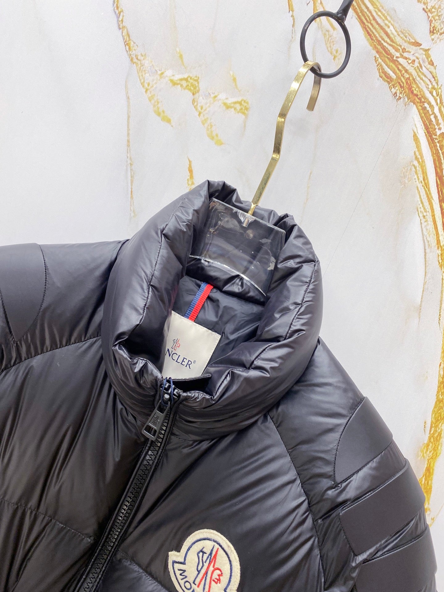 Moncler long puffer jacket close-up, dark navy hooded collar and logo badge