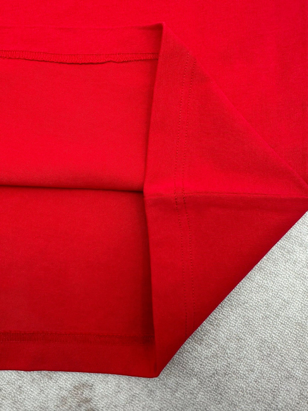 Red T-shirt folded view showing side panel and stitched seams