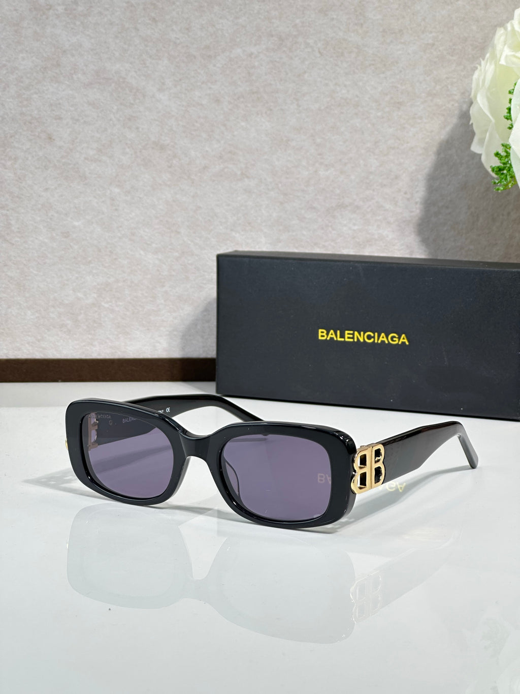 Sunglasses with black frames, purple lenses, and gold logo detailing