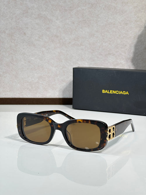 Sunglasses with black frames, brown lenses, and gold logo detailing at temples