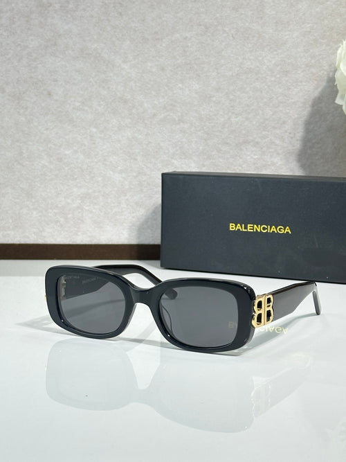 Sunglasses with dark frames, gray lenses, and gold logo hardware at the temples